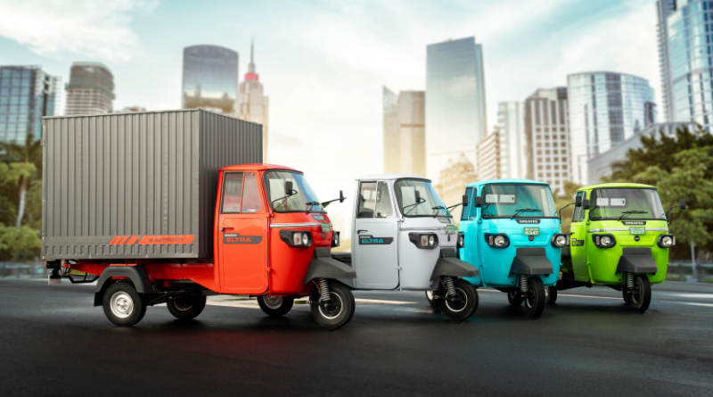 Electric rickshaws in various colors displayed on a city street with modern skyscrapers in the background.