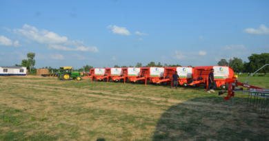 a row of farm equipment parked in a field