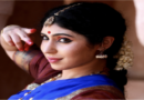 A woman dressed in traditional Indian attire poses gracefully for a photograph, showcasing vibrant colors and intricate designs.