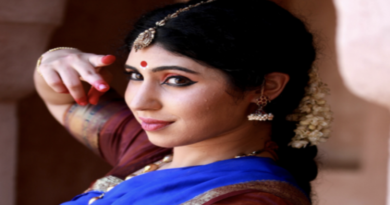 A woman dressed in traditional Indian attire poses gracefully for a photograph, showcasing vibrant colors and intricate designs.