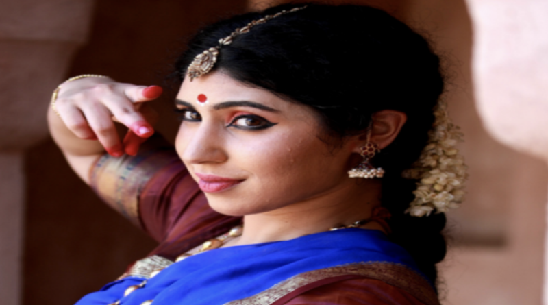 A woman dressed in traditional Indian attire poses gracefully for a photograph, showcasing vibrant colors and intricate designs.